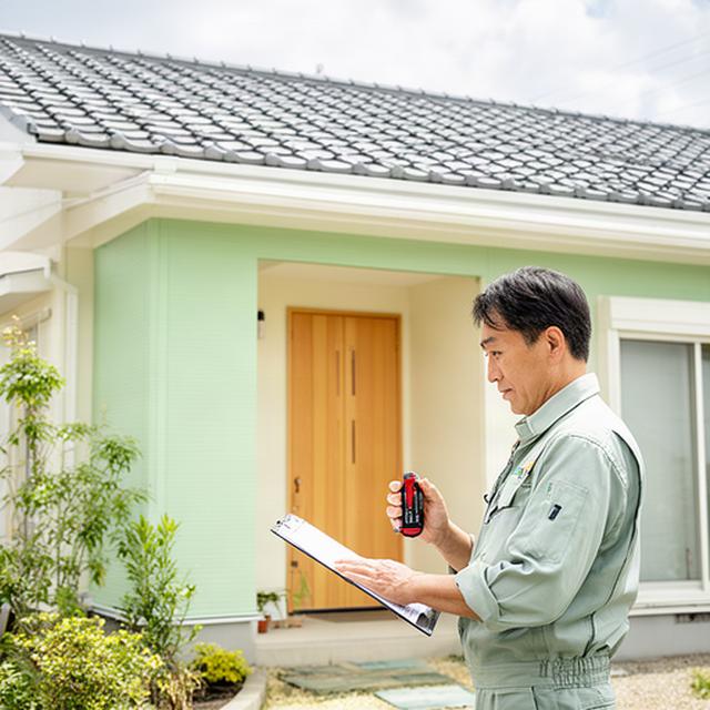 大分市の戸建て住宅を点検する職人と明るい外観の住まい