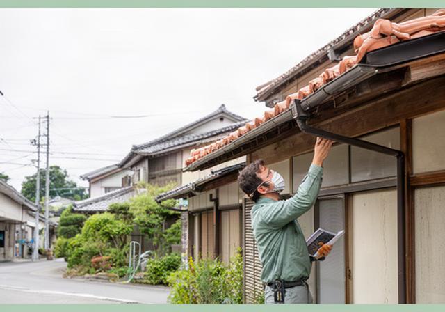 大分市の住宅で屋根と外壁を確認する修理スタッフ、落ち着いた住宅街の現地調査風景